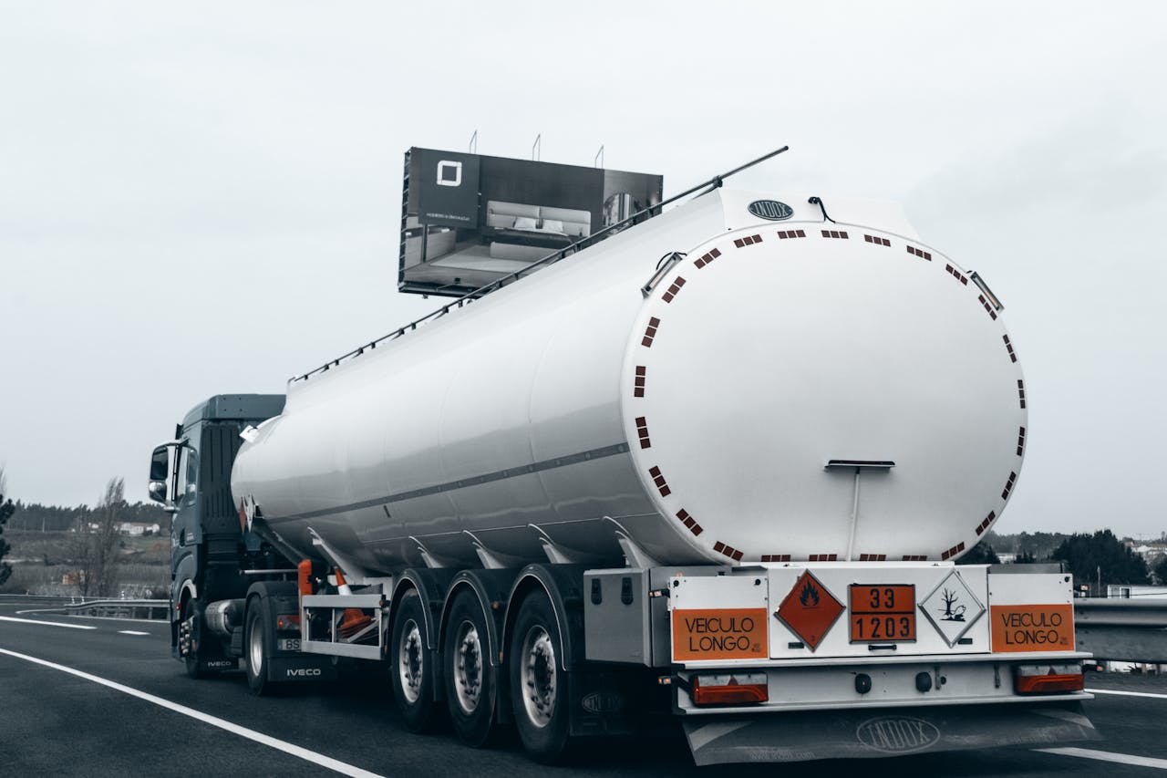 about-img Rear view of a large tanker truck transporting fuel on a highway, emphasizing logistics and transportation.