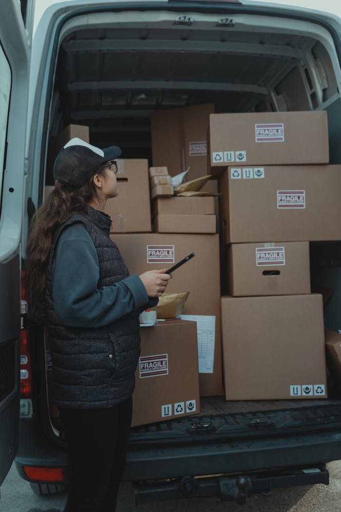 gallery-02 A female delivery worker organizing packages marked fragile in the back of a delivery van.