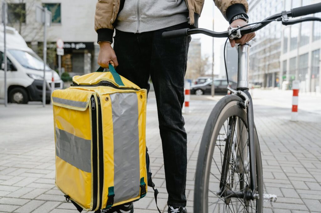 Service 01 Delivery cyclist in city holding a large thermal bag, ready for service.